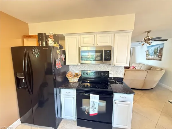 a kitchen with stainless steel appliances granite countertop a refrigerator a stove and a sink with wooden floor