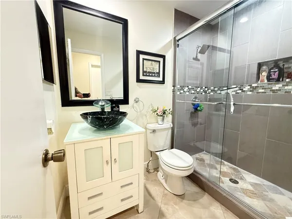 a bathroom with a granite countertop sink a toilet a mirror and shower