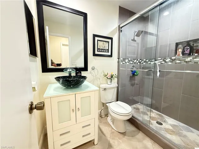 a bathroom with a granite countertop sink a toilet a mirror and shower