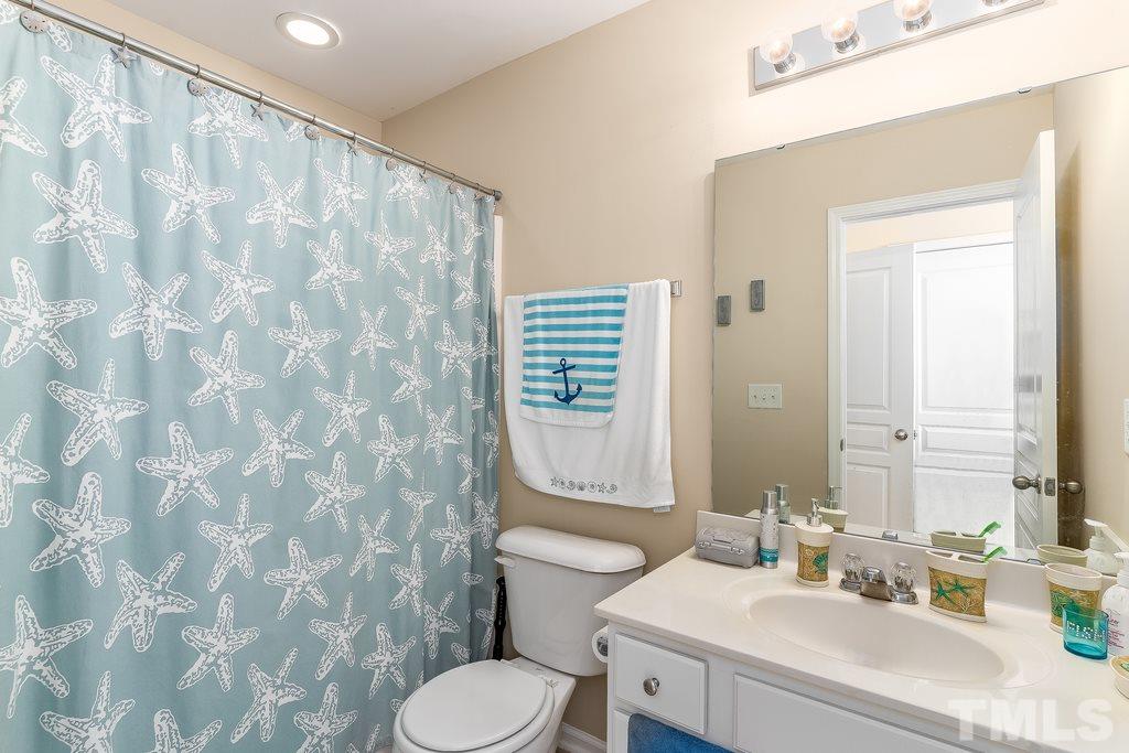 7606 Winners Edge Street Raleigh, NC 27617 - Photo 14 of 25 a bathroom with a sink a toilet and shower curtain