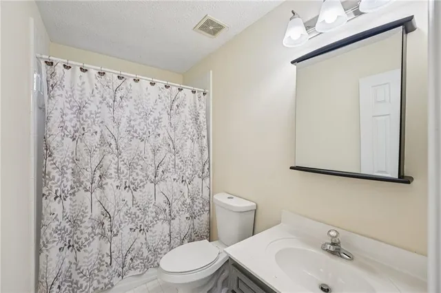 a bathroom with a sink a toilet and shower curtain