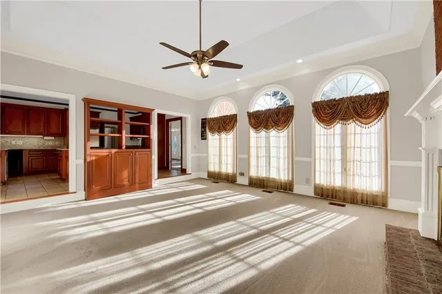 a view of an empty room with chandelier fan and a window