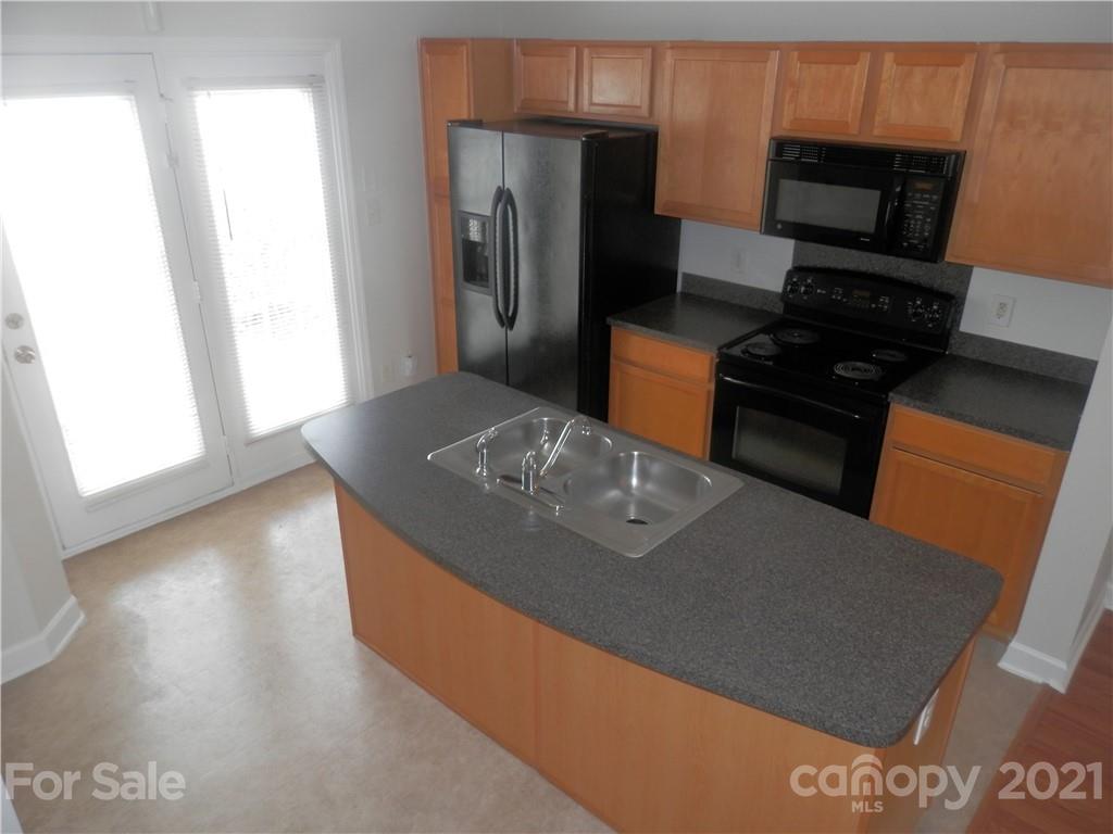 5057 Prosperity Church Road Charlotte, NC 28269 - Photo 11 of 24 a kitchen with stainless steel appliances a stove a microwave a refrigerator a sink and a dining table
