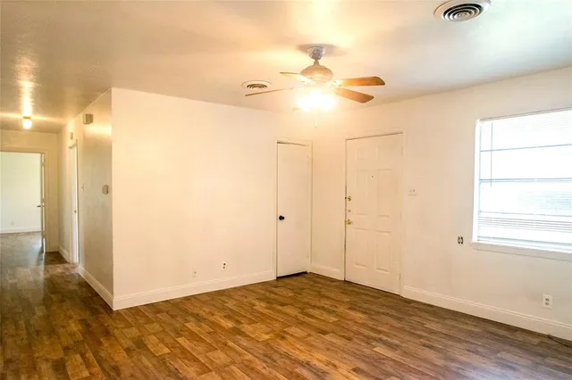 an empty room with wooden floor and fan chandelier