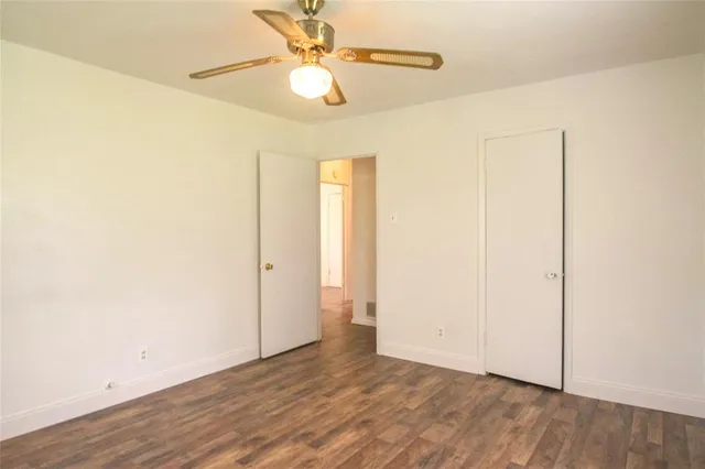 an empty room with wooden floor and fan