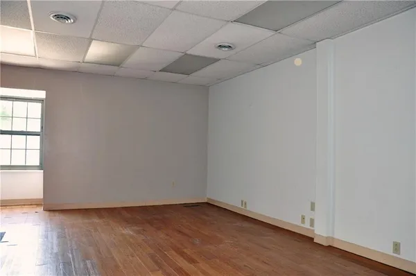 an empty room with wooden floor and windows with curtains