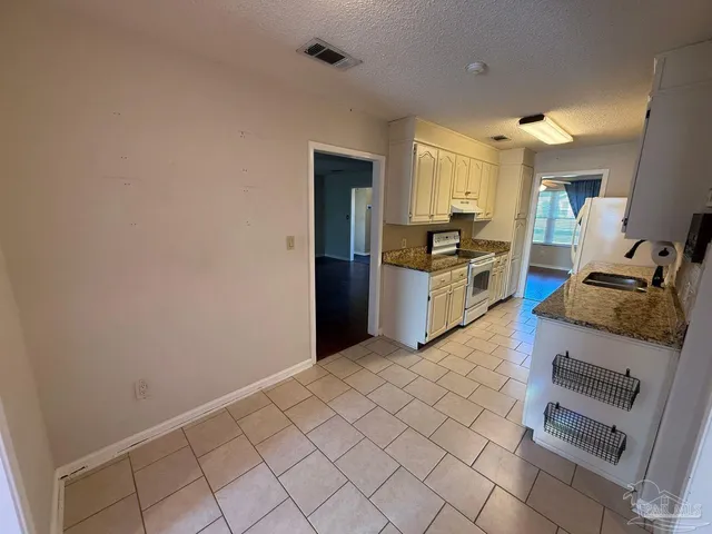a kitchen with granite countertop white cabinets and stainless steel appliances