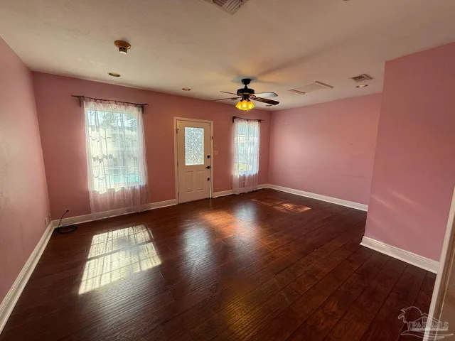 a view of empty room with wooden floor and fan