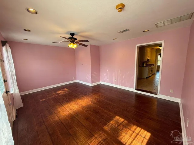 a view of an empty room with a window and wooden floor