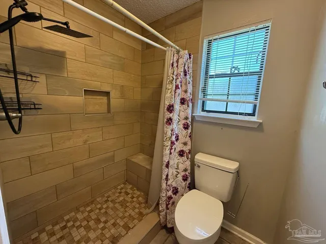 a white toilet sitting next to a shower curtain