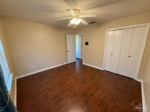 an empty room with wooden floor and a ceiling fan