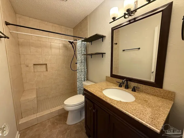 a bathroom with a granite countertop sink toilet and shower