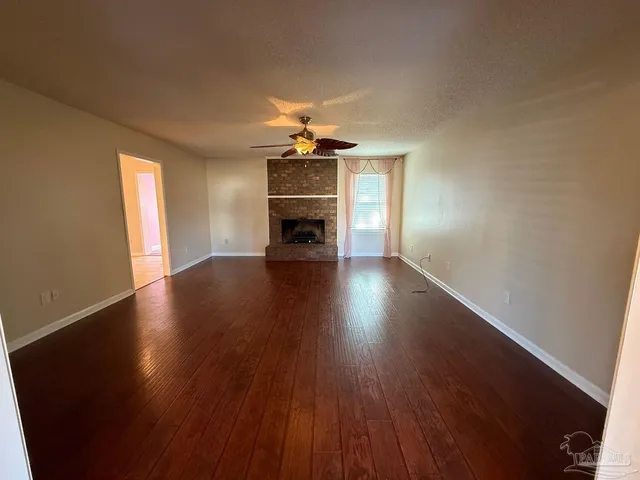 an empty room with wooden floor fireplace and windows