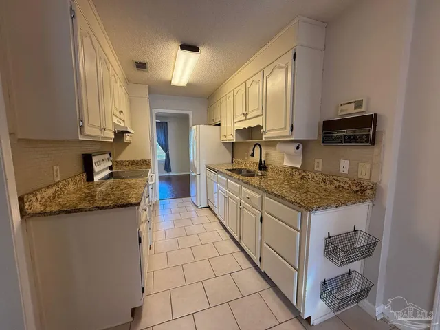 a kitchen with granite countertop a sink stove and cabinets
