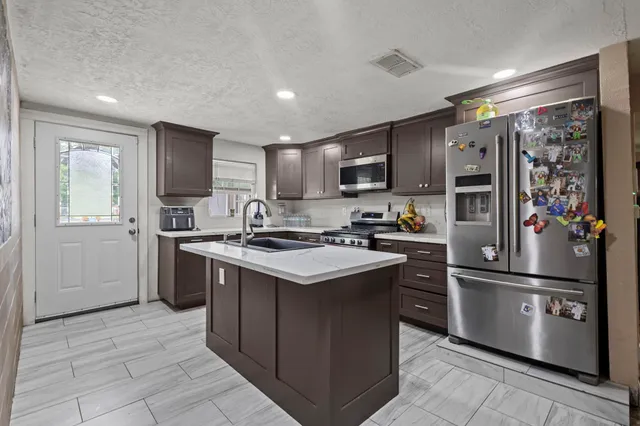 a kitchen with stainless steel appliances granite countertop a refrigerator stove microwave and sink