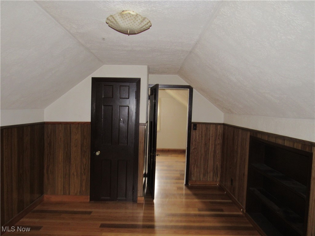 4550 Effie Road Cleveland, OH 44105 - Photo 19 of 29 Additional living space with wooden walls, lofted ceiling, dark wood-type flooring, and a wainscoted wall