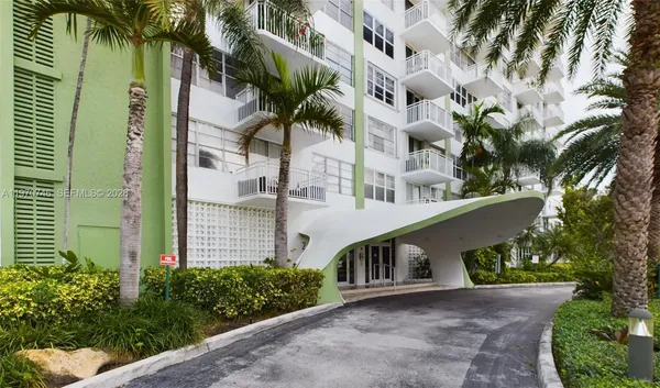 a front view of multi story residential apartment building with yard and parking space