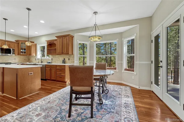 a open kitchen with stainless steel appliances granite countertop a stove a sink a dining table and chairs with wooden floor