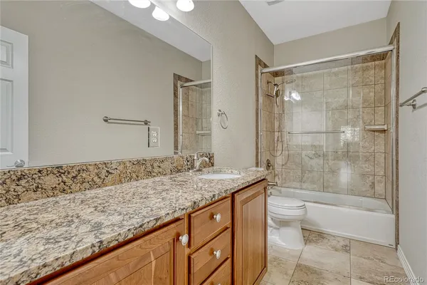 a bathroom with a granite countertop sink a toilet and bathtub