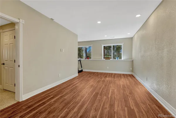 a view of an empty room with wooden floor and a window