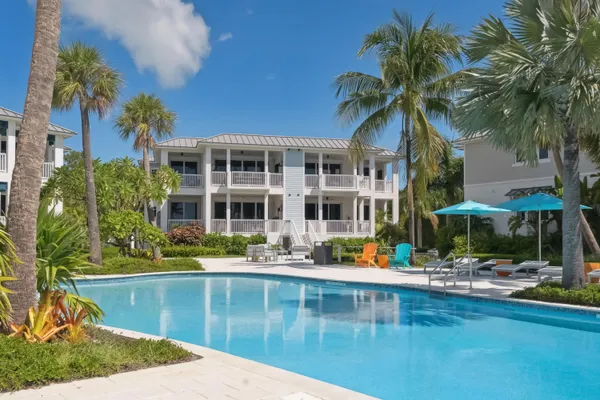 a front view of a house with swimming pool and glass windows and plants