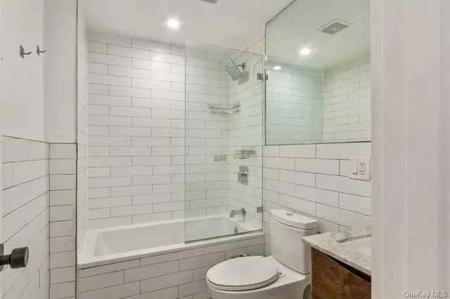 a bathroom with a bathtub shower sink mirror and toilet
