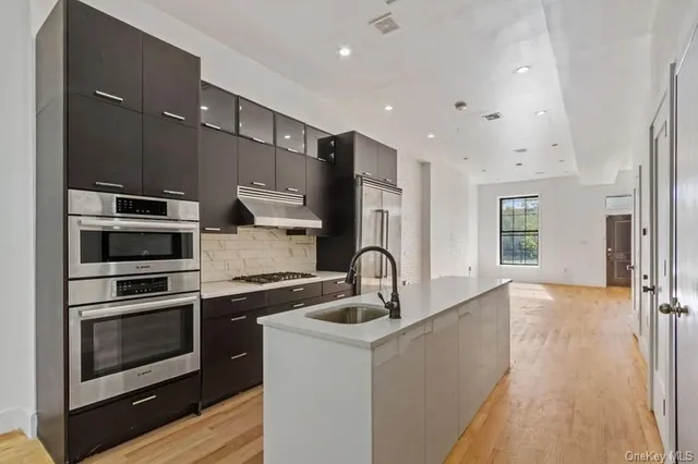 a kitchen with stainless steel appliances kitchen island granite countertop a stove and a sink