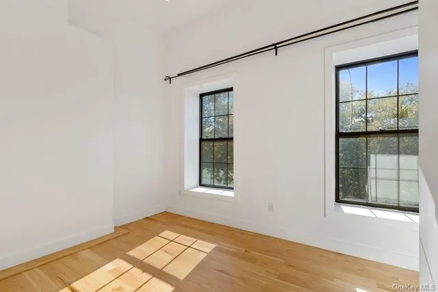 a view of an empty room with a window and wooden floor