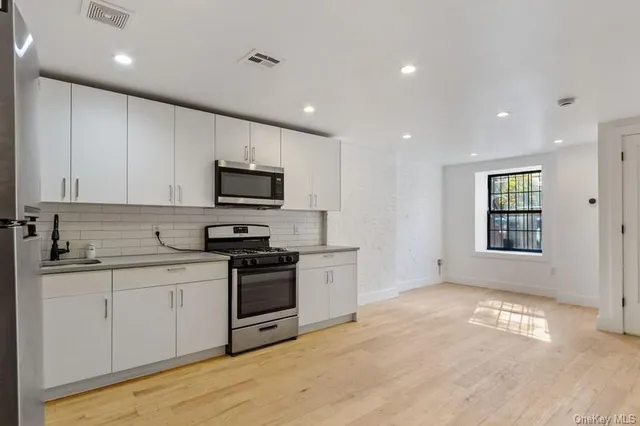 a kitchen with stainless steel appliances granite countertop a stove a sink and a microwave