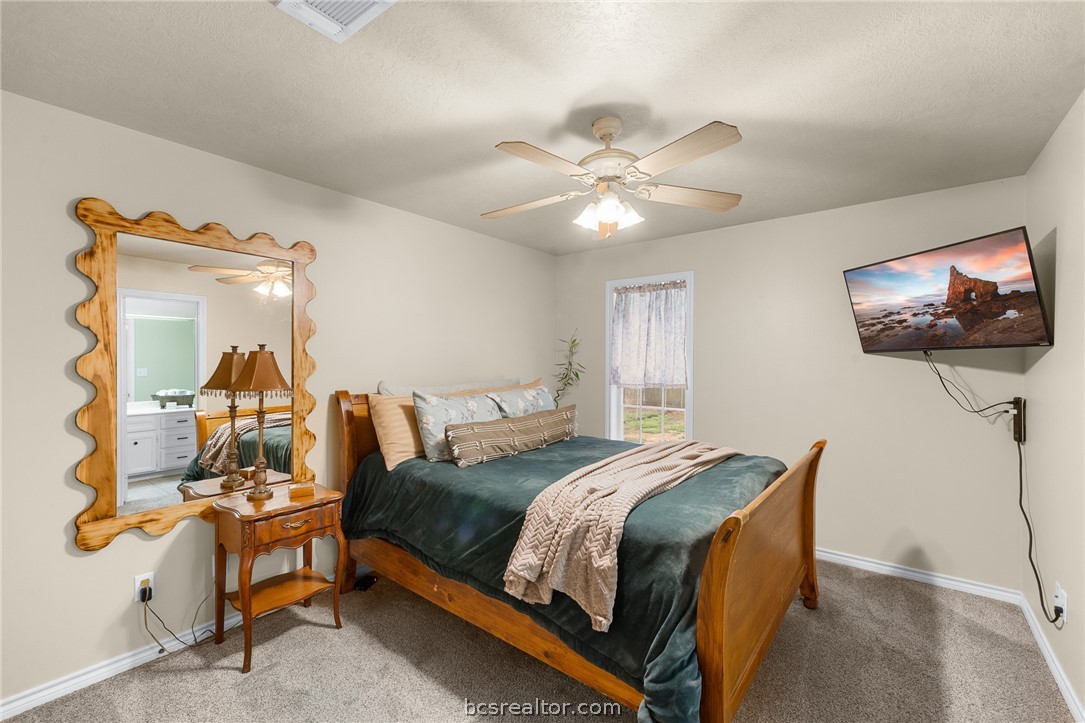 2287 North Earl Rudder Freeway Bryan, TX 77803 - Photo 3 of 32 a bedroom with a bed a mirror on dresser and a chandelier