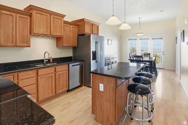 14820 175 East Draper, UT 84020 - Photo 5 of 39 Kitchen featuring a center island, light wood-style floors, pendant lighting, brown cabinetry, and a kitchen bar