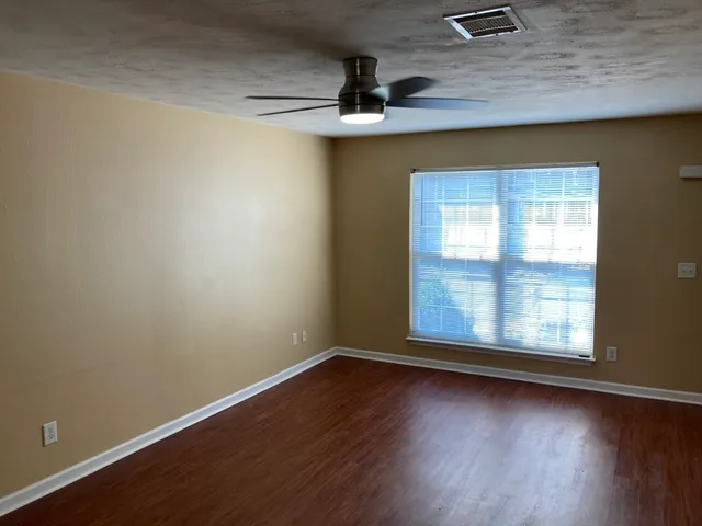 an empty room with wooden floor and windows