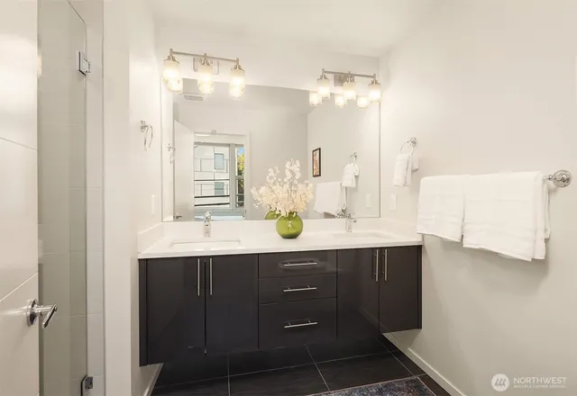 a bathroom with a sink double vanity granite tub shower and a mirror