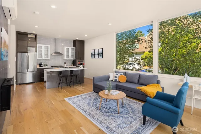 a living room with stainless steel appliances kitchen island granite countertop furniture and a rug