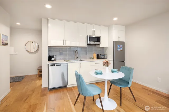 a kitchen with stainless steel appliances a dining table chairs refrigerator and sink
