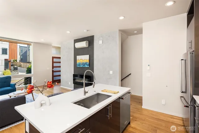 a room with stainless steel appliances kitchen island a sink and a view of living room