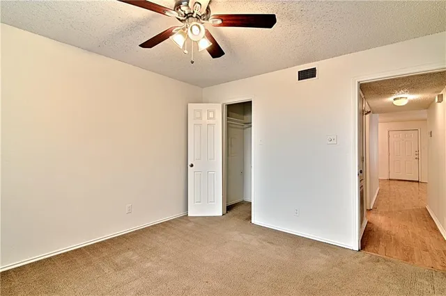 an empty room with closet and a chandelier fan