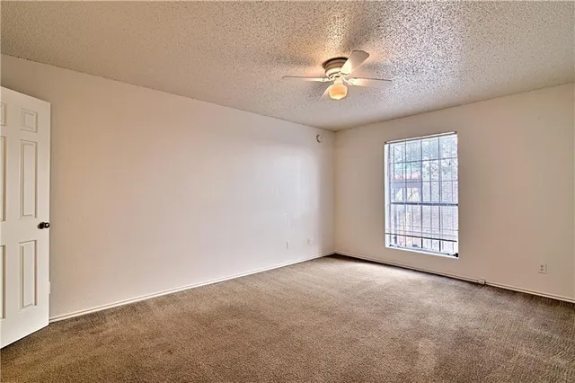 an empty room with windows and chandelier fan
