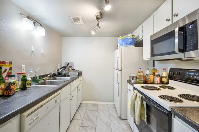a kitchen with granite countertop a sink stove and refrigerator
