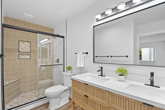 a bathroom with a granite countertop sink a toilet a mirror and shower