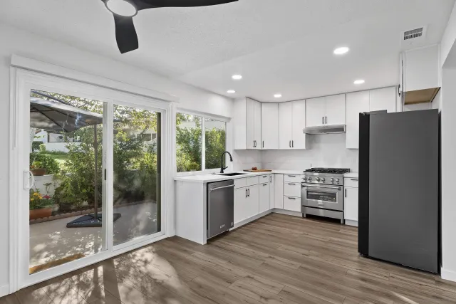 a kitchen with stainless steel appliances granite countertop a refrigerator a stove a sink and a granite counter tops with wooden floors