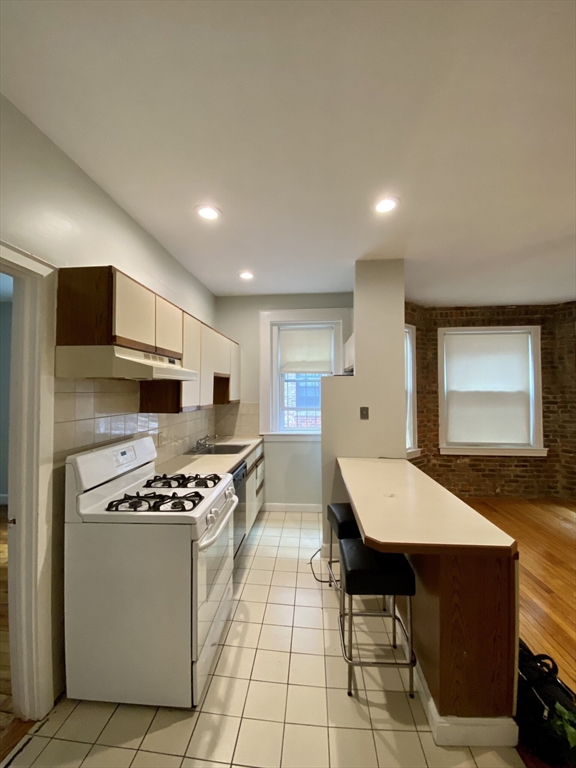 16 Royce Road, Unit 4 Boston, MA 02134 - Photo 2 of 4 a kitchen with stainless steel appliances kitchen island granite countertop a stove a sink and a microwave