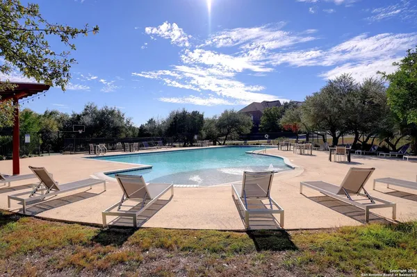 a view of swimming pool with seating space and trees in the background