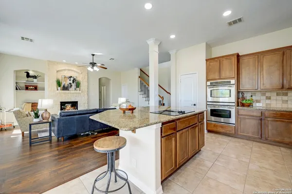 a kitchen with stainless steel appliances granite countertop a sink dishwasher stove and wooden cabinets with wooden floor