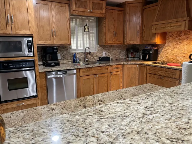 a kitchen with stainless steel appliances granite countertop a stove a sink and a microwave