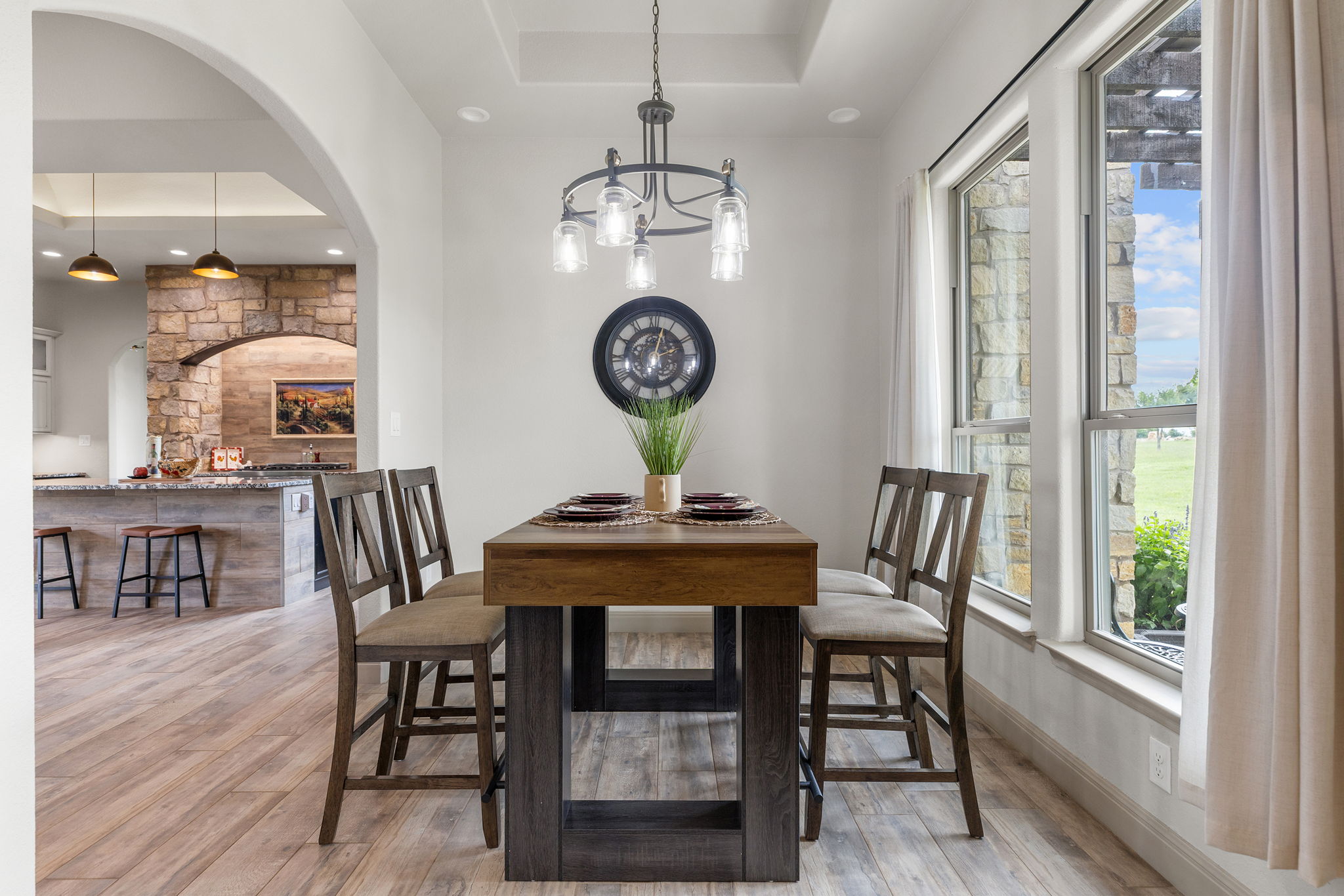 128 Strada Luca Florence, TX 76527 - Photo 13 of 40 Dining area with wood-look flooring, tray ceiling, modern chandelier, and large windows bringing in natural light.