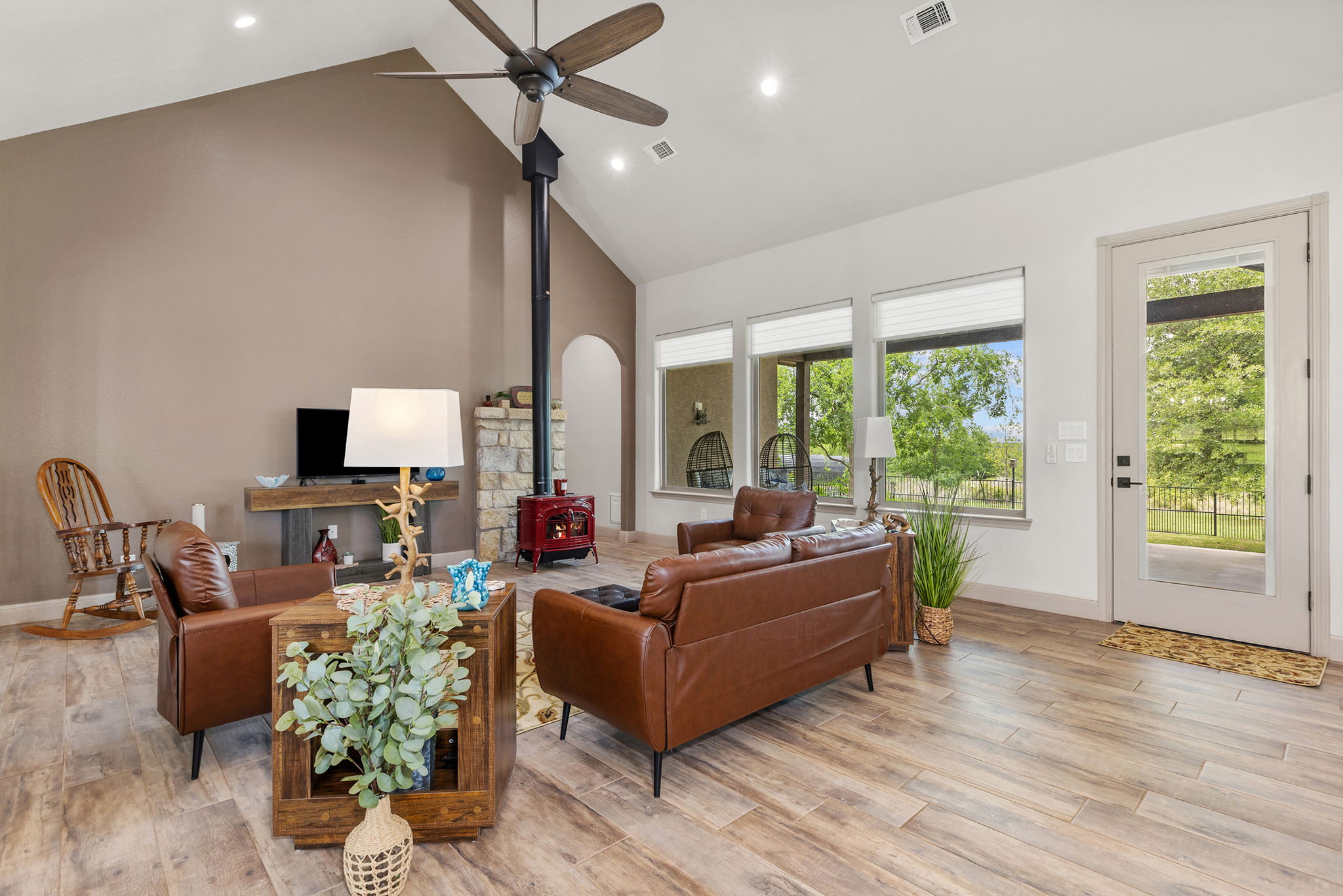 128 Strada Luca Florence, TX 76527 - Photo 14 of 40 Living area with vaulted ceilings, wood-look flooring, stone accents, large windows, and direct access to the outdoor space.