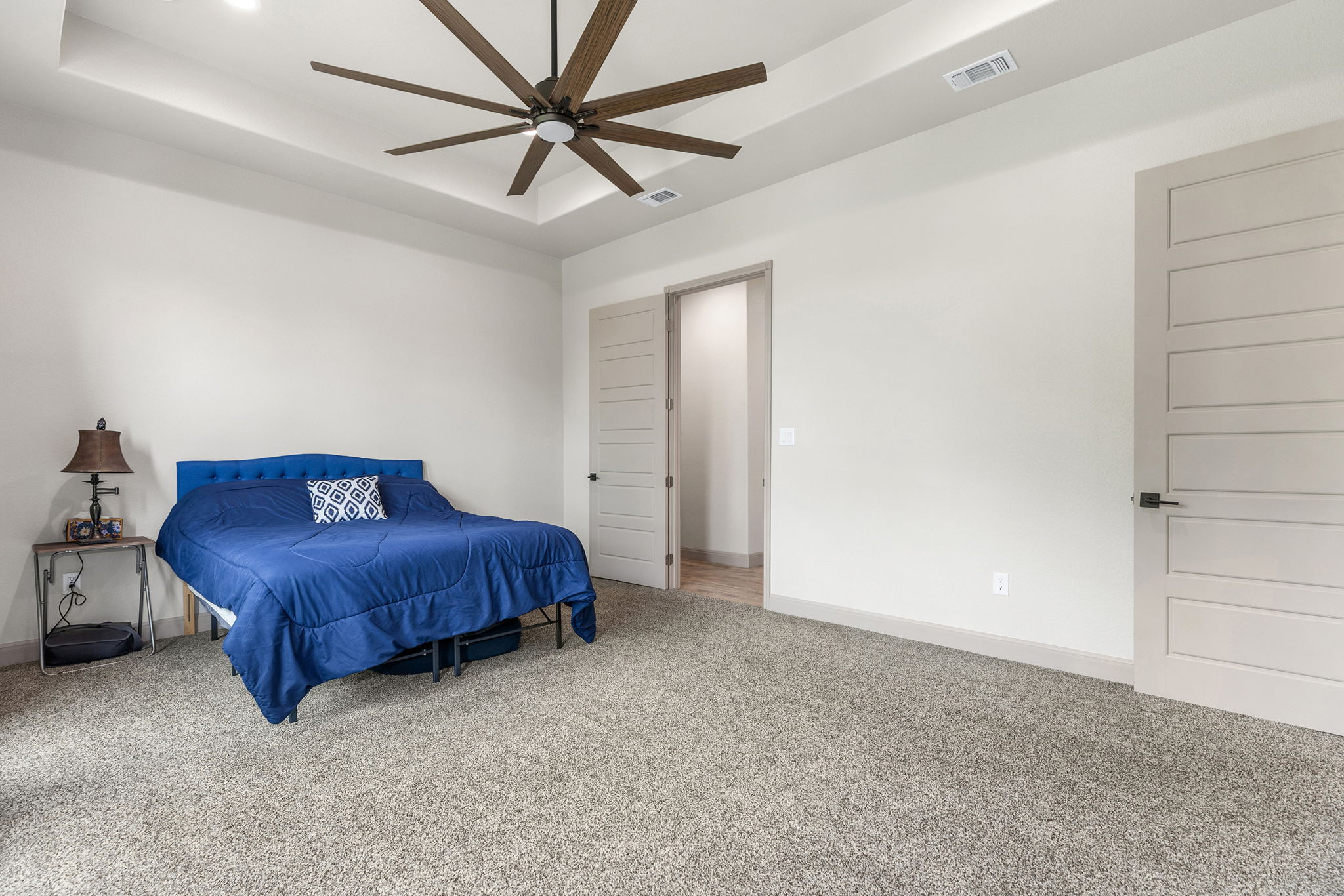 128 Strada Luca Florence, TX 76527 - Photo 17 of 40 Spacious bedroom with tray ceiling, recessed lighting, large ceiling fan, neutral carpet, and modern paneled doors.