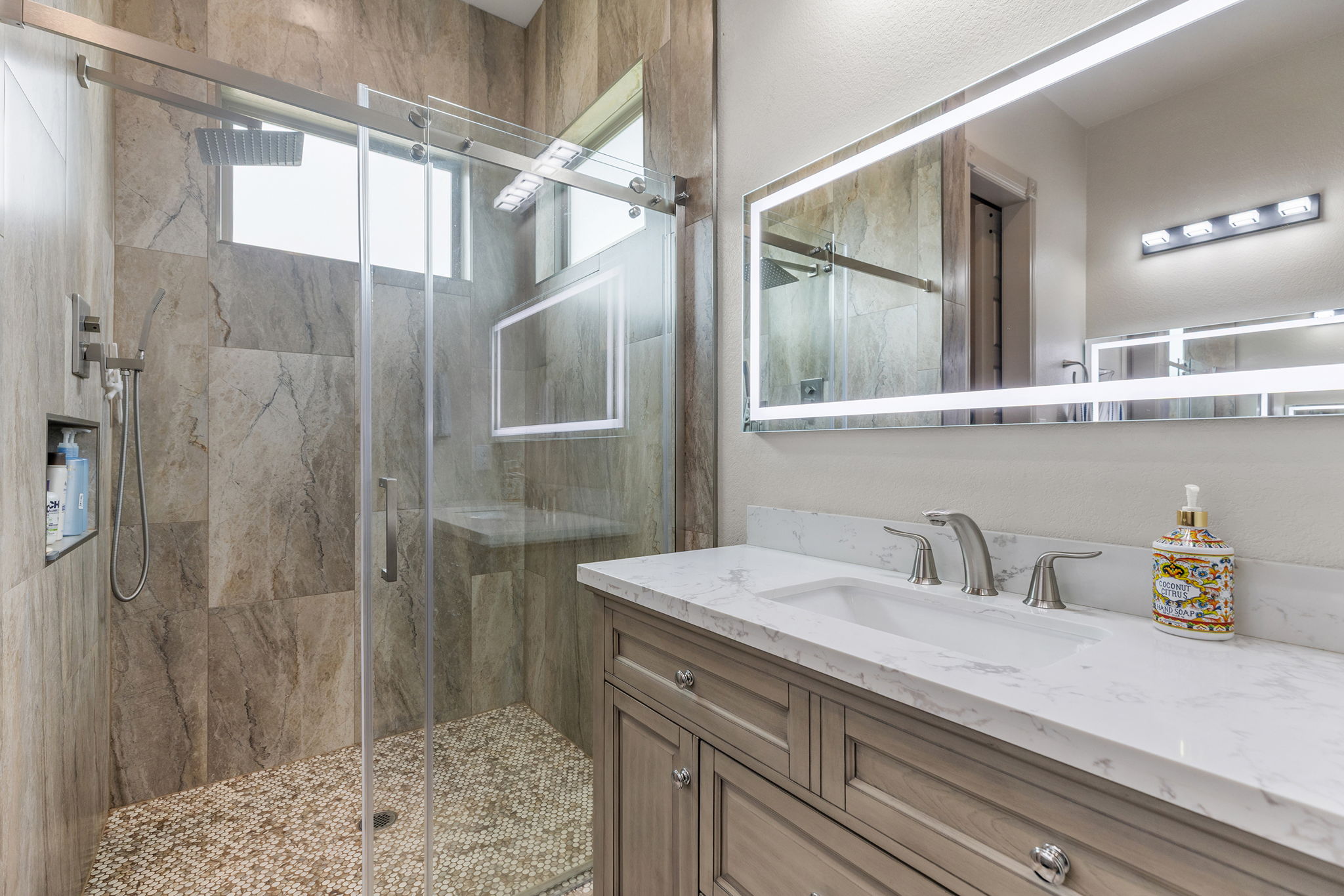 128 Strada Luca Florence, TX 76527 - Photo 20 of 40 Bathroom featuring a light gray wood-finish vanity with a marble-look countertop, illuminated mirror, modern fixtures, and a decorative tile-accent electric fireplace.