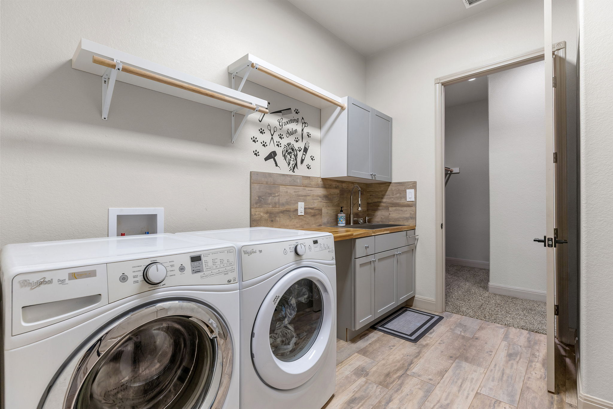 128 Strada Luca Florence, TX 76527 - Photo 23 of 40 Laundry room with wood-look flooring, built-in cabinetry, utility sink, wall-mounted shelving, and hanging rod for added functionality.